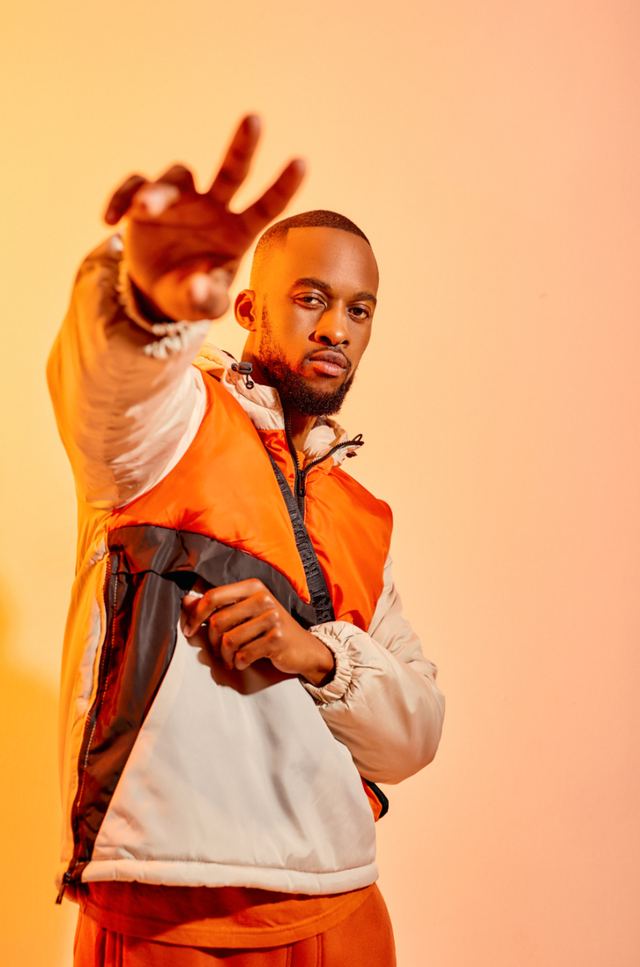 Model in orange and cream jacket against an orange backdrop