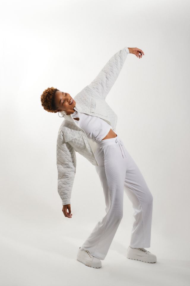 Model in all white leaning back on a white set