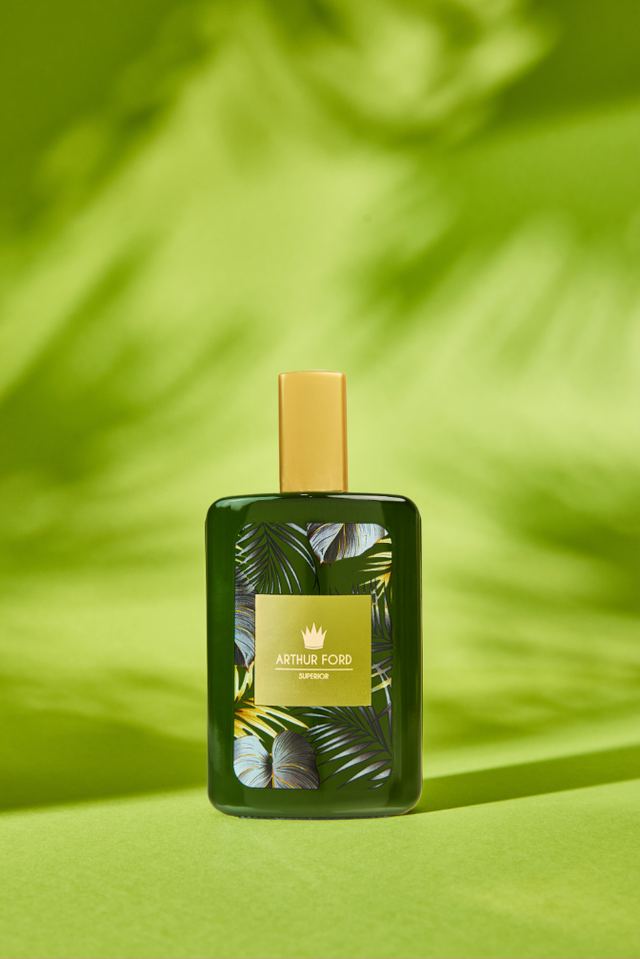 Green Exotic Desire bottle in palm-leaf shadow