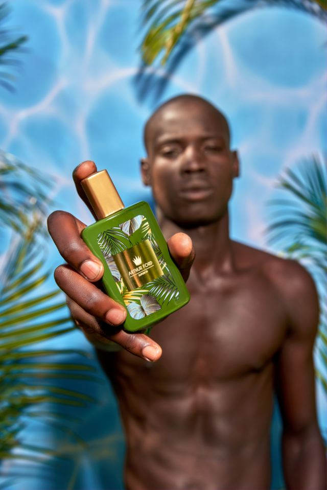 Model holding a green Exotic Desire bottle toward the camera
